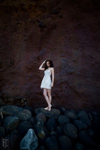 a woman in a white dress standing on rocks